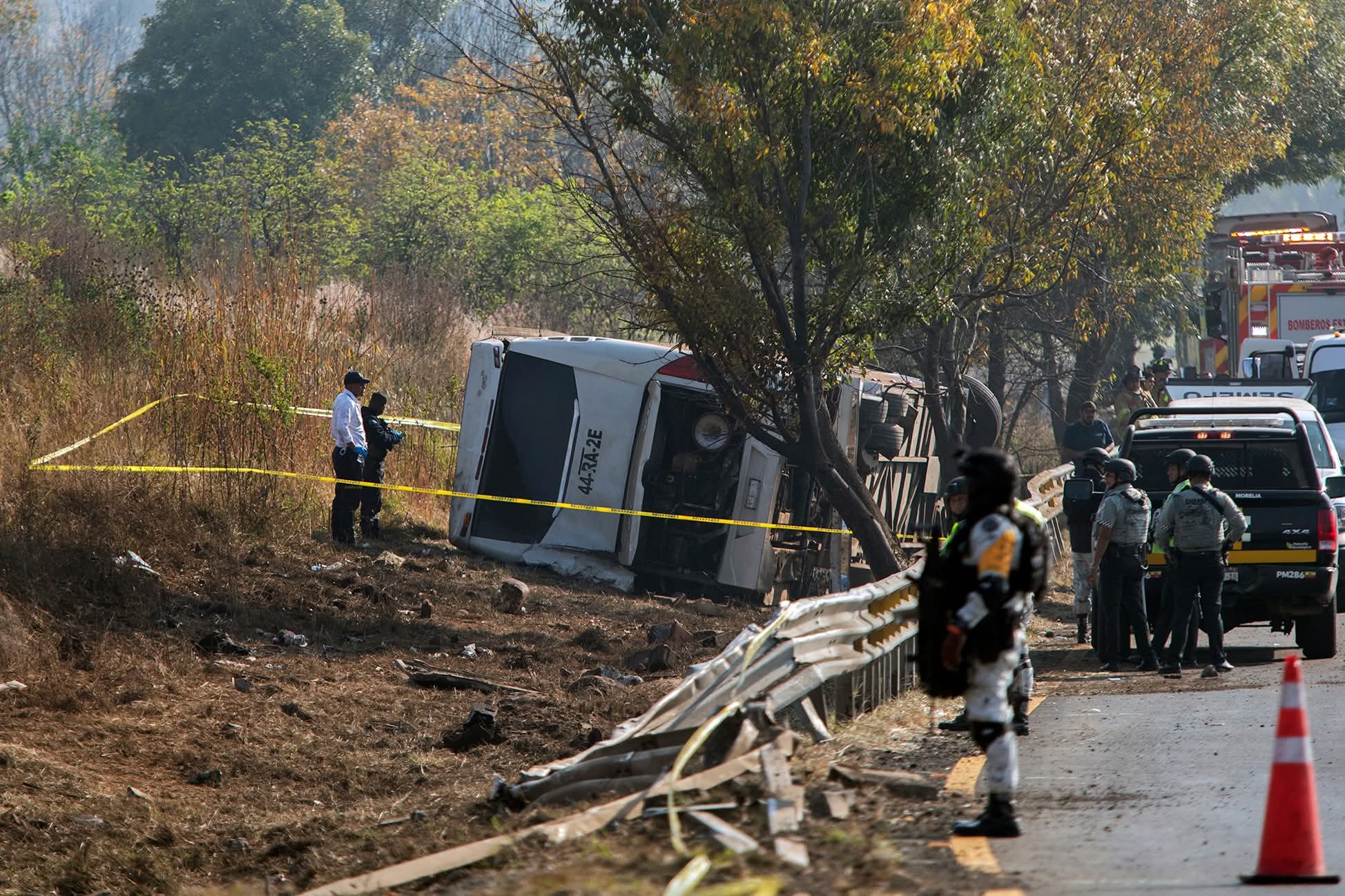 Emergency responders, along with personnel from the Michoacan State Attorney Generals Office, the National Guard, and the Army, work at the scene of a bus crash on the MoreliaPatzcuaro highway near the community of Tiripetio, state of Michoacan, Mexico, on November 22, 2025. A tour bus crashed and overturned, leaving at least 10 people dead and more than 20 injured, authorities reported. (Photo by ENRIQUE CASTRO / AFP)