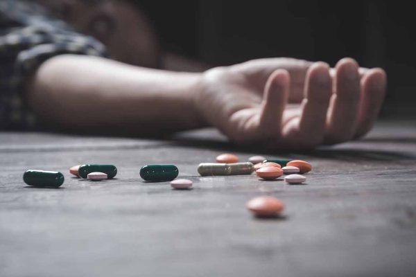 The man committing suicide by overdosing on medication. Close up of overdose pills and addict.
