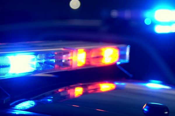 Emergency lights flashing on police cars at night at the scene of an accident or crime. Focus shifts from lights in the foreground to the lights in the background.